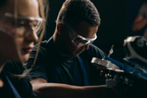 Students focused on robotics, wearing protective goggles, symbolizing teamwork and education in technology.